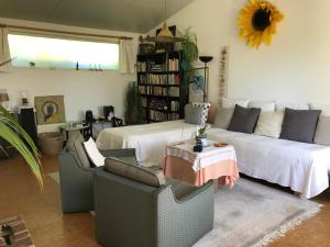 a living room with a white couch and chairs at B&B Koornemoezen in Zedelgem