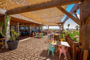 un patio avec des tables et des chaises sous un pavillon dans l'établissement Sunrise Beach Hotel, à Gruissan