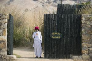 a woman is standing in front of a gate at Amritara Jawai Resort in Pāli