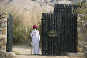 Amritara Jawai Resort في Pāli: امرأة تقف امام بوابة