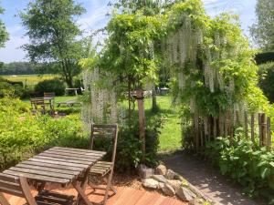 un jardín con una mesa de madera y una pérgola en B&B Koornemoezen en Zedelgem