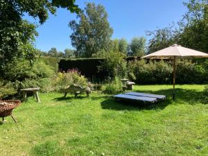 un jardín con sombrilla, banco y mesa en B&B Koornemoezen en Zedelgem
