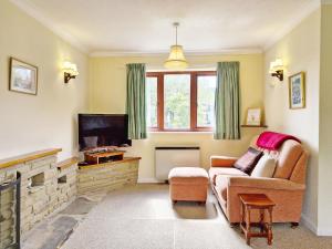 Bramley Cottage في Charlton: غرفة معيشة مع أريكة وتلفزيون