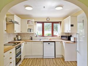 Bramley Cottage في Charlton: مطبخ مع دواليب بيضاء ونافذة
