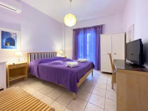 a bedroom with a purple bed and a flat screen tv at Manto Hotel in Mýkonos City
