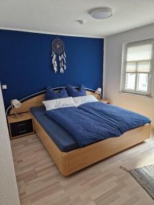 a bedroom with a large bed with a blue wall at Ferienhaus Reschwitzer Auszeit in Saalfeld