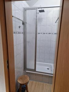 a bathroom with a shower with a stool and a tub at Ferienhaus Reschwitzer Auszeit in Saalfeld +19 photos