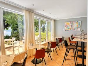 a restaurant with tables and chairs and windows at Seespitz Gästehaus in Herrsching am Ammersee
