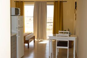 a room with a desk and a table and a refrigerator at Beauty Plaza Apartaments in Santa Maria