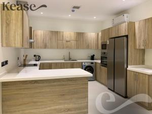 a kitchen with wooden cabinets and a black refrigerator at Kease Tawun A1-8 Royal touch Balcony GZ41 in Riyadh