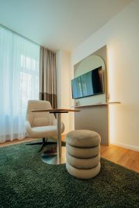 a living room with a table and a chair and a television at Hotel Barbarossa Classic in Ratingen