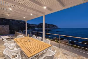 einen Holztisch und Stühle auf einem Balkon mit Meerblick in der Unterkunft Hamilton Sea Front Villa in Archangelos