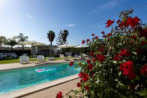 a swimming pool with red flowers in the foreground at Torre del mare in Menfi