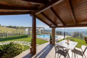 un patio al aire libre con mesa, sillas y piscina en Casa Grazia, en San Giorgio di Pesaro