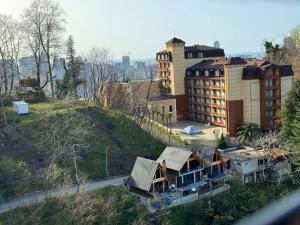 a house on top of a hill next to a building at Panorama BatumGora in Batumi