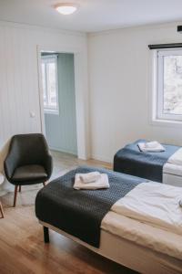 una habitación de hotel con 2 camas y una silla en Røvær KulturHotell, en Røvær