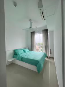 ein Schlafzimmer mit einem Bett mit grüner Bettwäsche und einem Fenster in der Unterkunft 2 Bedroom Apartment in Sri Jayewardenepura Kotte