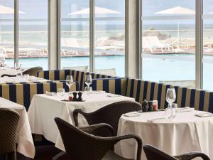 Sofitel Biarritz Le Miramar Thalassa في بياريتز: مطعم بطاولات وكراسي مطل على المحيط