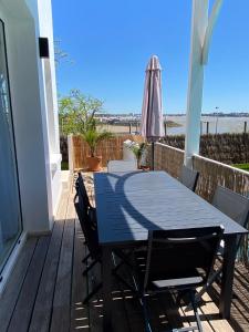 a table and chairs on a deck with an umbrella at Villa face mer in Royan