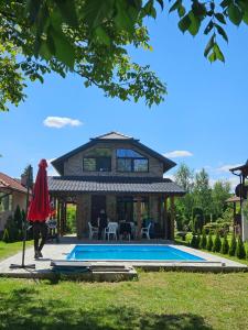 une personne marchant devant une maison avec piscine dans l'établissement Vikendica na Drini, à Banja Koviljača