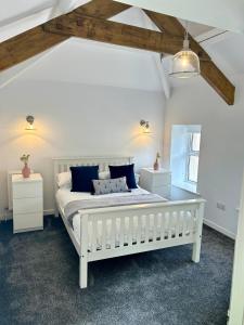 a bedroom with a white bed with blue pillows at The Cottage, Bridge House in Laxey