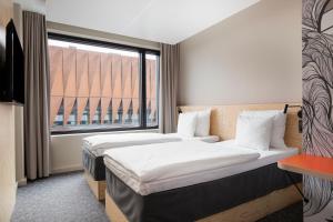 two beds in a room with a large window at Heymo 1 by Sokos Hotels in Espoo
