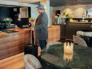 a man is standing at a counter with a table at Best Western Plus John Bauer Hotel in Jönköping