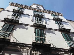a tall white building with green shutters and balconies at Casa Tilde Bacoli in Bacoli