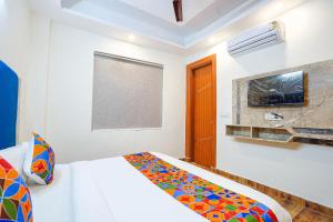 a white bedroom with a bed and a tv at FabHotel The Luxe Inn in New Delhi