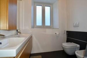 baño con lavabo y aseo y ventana en Tutti insieme a Caldonazzo, en Caldonazzo