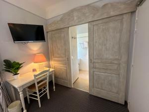 een kamer met een bureau en een tv aan de muur bij Le Relais Notre Dame in Quinson