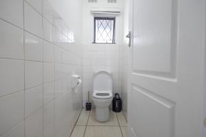 a white bathroom with a toilet and a window at Safi Luxury Self-Catering Suite 8 in East London