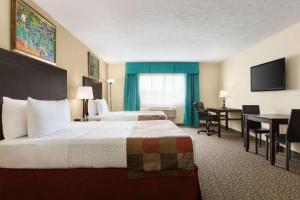 una camera d'albergo con un grande letto e una scrivania di Days Inn by Wyndham Montreal East a Montréal