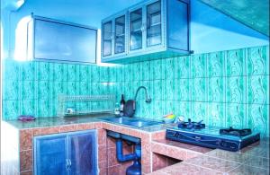 a kitchen with green tiled walls and a sink at KJ Purple House Senggigi in Senggigi