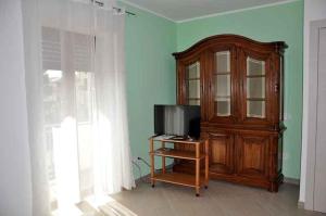 a living room with a television and a wooden cabinet at Cappuccini Guest House in San Giovanni in Fiore