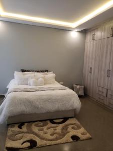 a bedroom with a large white bed with a rug at The V Space in Lusaka