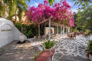 un patio con fiori rosa, tavoli e alberi di Radisson Blu Resort, Goa a Cavelossim