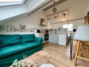 a living room with a green couch and a kitchen at Le Jardin des Plantes in Calais