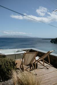 einen Tisch und einen Stuhl auf einer Terrasse mit Meerblick in der Unterkunft Aloe Comfort House by KHI in Kythnos