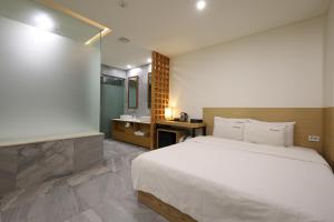 um quarto com uma grande cama branca e um lavatório em TRT Hotel em Busan