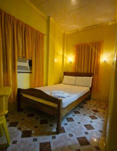 1 dormitorio con 1 cama en una habitación amarilla en Drossgold Pension House, en Tubigon