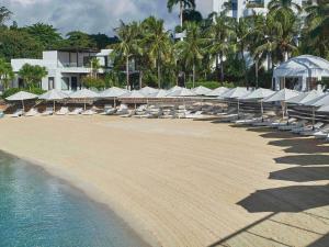 a beach with lounge chairs and umbrellas and the water at Mövenpick Hotel Mactan Island Cebu in Mactan