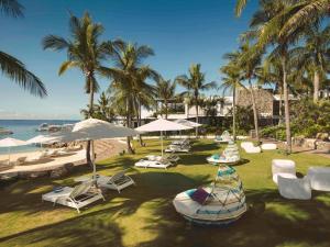una spiaggia con sedie e ombrelloni e l'oceano di Mövenpick Hotel Mactan Island Cebu a Mactan