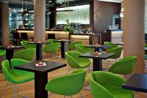 un restaurante con sillas y mesas verdes y un bar en Green Village Eco Resort en Lignano Sabbiadoro