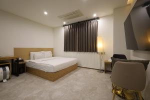 um quarto com uma cama, uma secretária e uma cadeira em TRT Hotel em Busan