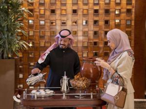un hombre y una mujer parados frente a una mesa en Raffles Makkah Palace en Makkah