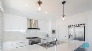 a white kitchen with a sink and a refrigerator at Beachside Oasis in Caves Beach