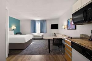 ミッドベールにあるMainStay Suites Salt Lake City Fort Unionのベッドとデスクが備わるホテルルームです。