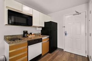 eine Küche mit weißen Schränken und einem schwarzen Kühlschrank in der Unterkunft MainStay Suites Salt Lake City Fort Union in Midvale