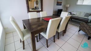 comedor con mesa de madera y sillas blancas en The Pelicans Rest en Teralba